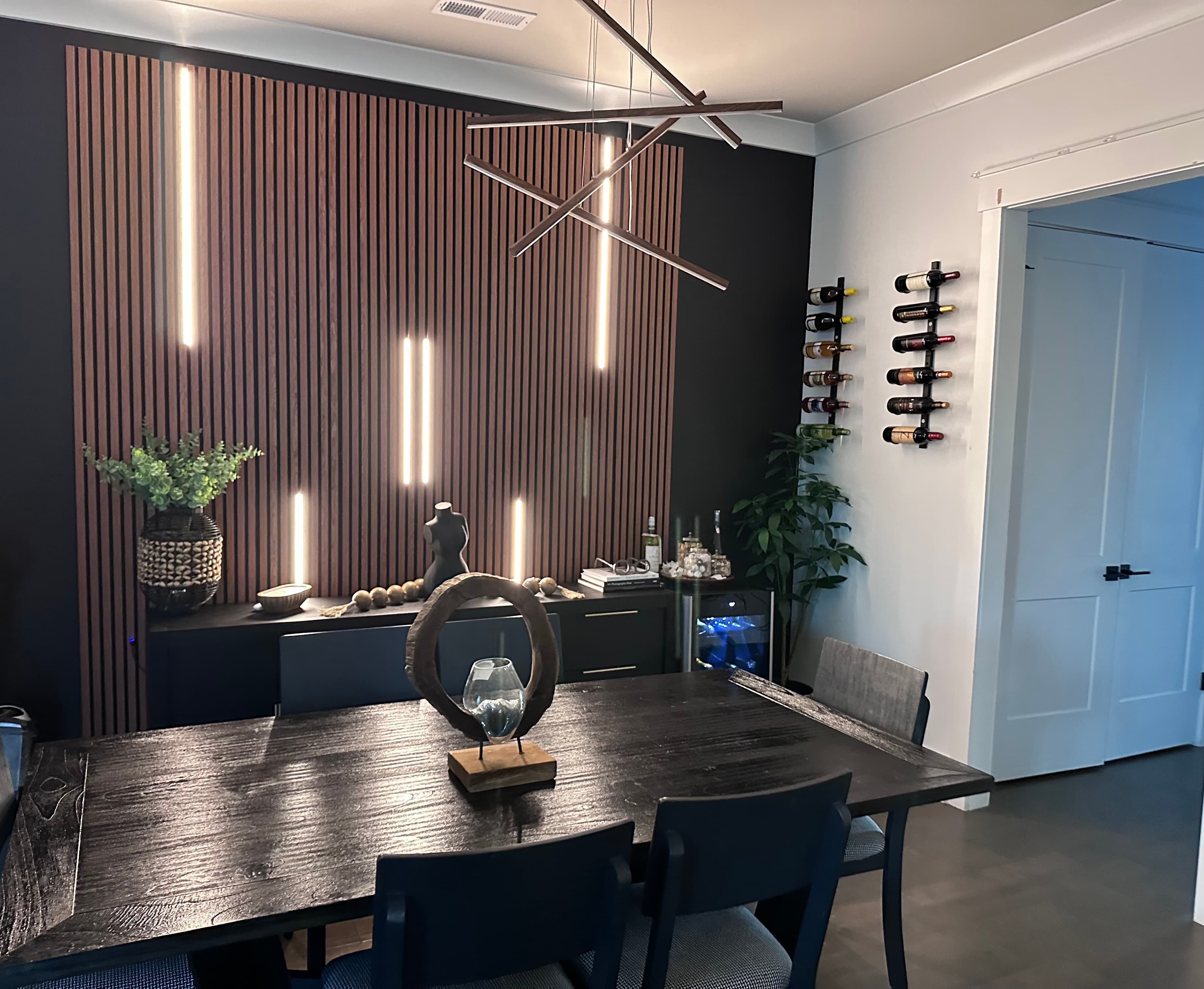 Dining room — dark wood slat wall and modern chandelier