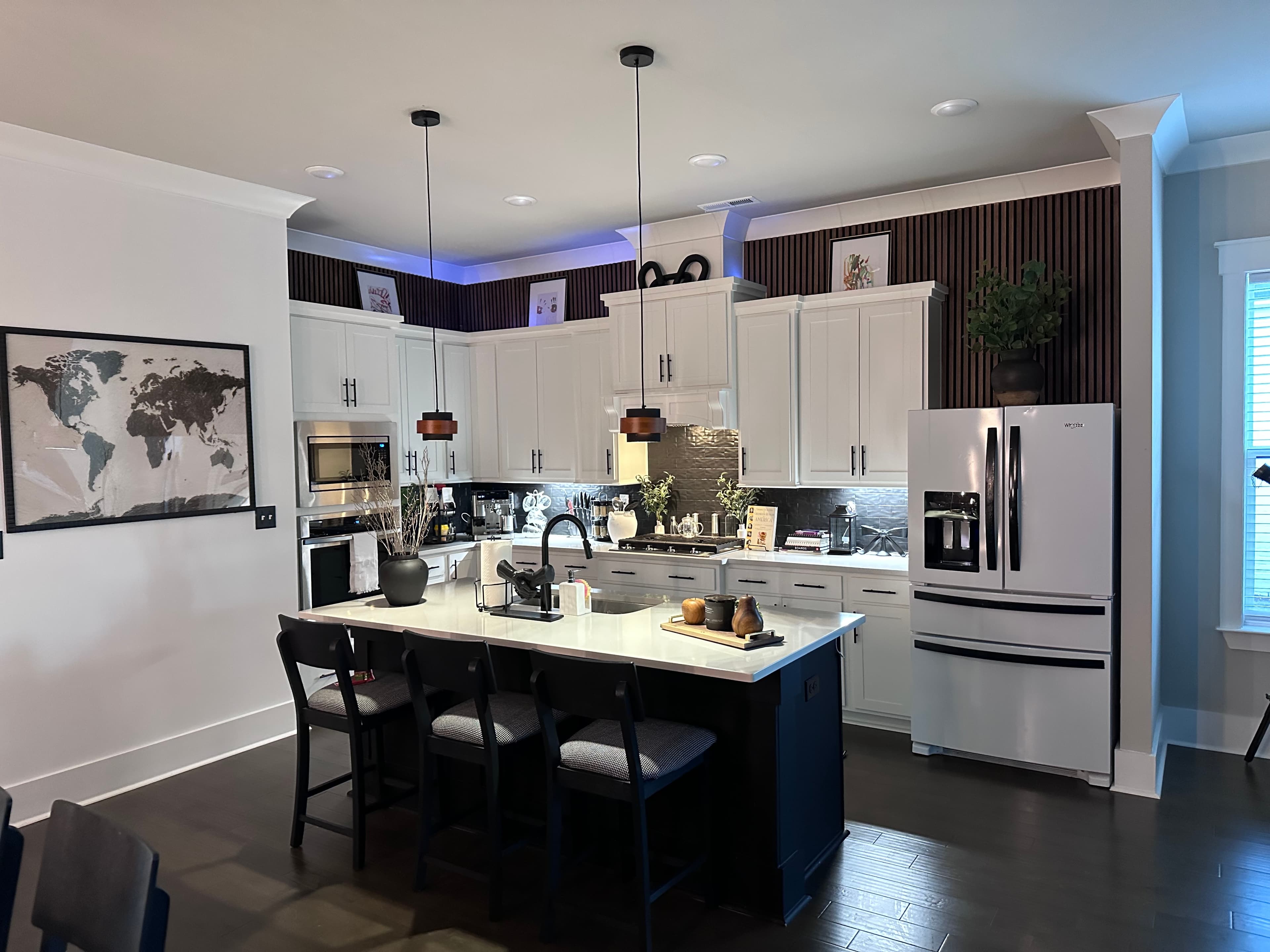 Open concept kitchen — white cabinets, dark island, slat accent wall